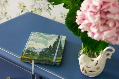 Notebook diary book on a blue table with bouquet of pink hydrangeas in the ro Stock Photos