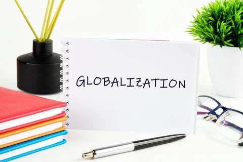 A notebook displaying the word globalization is placed on a desk next to vi.. Stock Photos