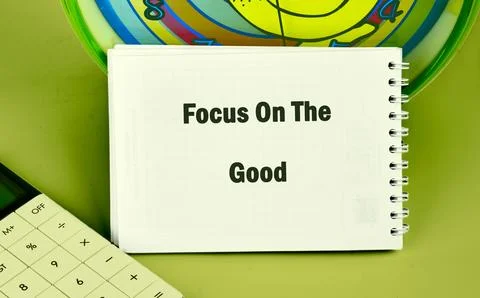 A notebook displays the phrase Focus On The Good, next to a calculator, with a Stock Photos