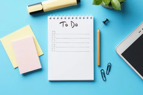 A notebook with to-do list on a blue desk with stationery. Stock Photos