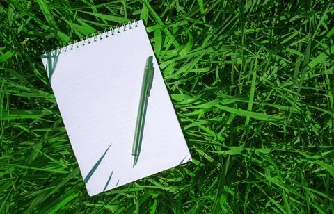 Notebook on the grass, spiral notepad with blank sheet, pencil and notebook Stock Photos