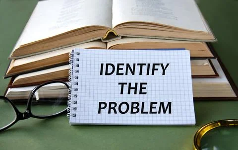 Notebook with IDENTIFY THE PROBLEM text on a green background with books an.. Stock Photos