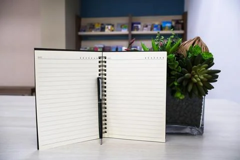 Notebook with lines page and black pen on wooden table background Stock Photos