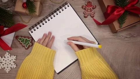 Notebook lying on wooden table among Christmas decorations and girl's hands Stock Footage 287502805