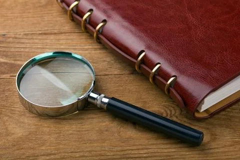 Notebook with a magnifier on wood table Stock Photos