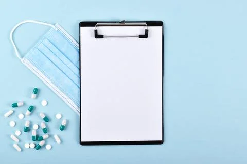 A notebook with a mask and capsules on a blue background with a place for tex Stock Photos