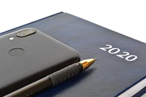 Notebook for new year with text 2020 on cover, pen and smartphone of rear side Stock Photos