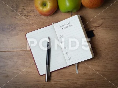 Notebook with New Year's resolutions surrounded by apples and a fountain pen Stock Photos