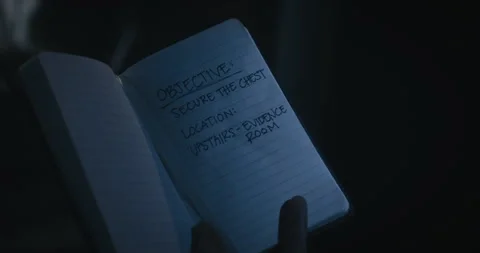Notebook with objectives written inside being raised up in darkness and dim Stock Footage 337269834