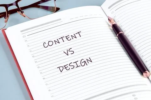 A notebook is open to a blank page with the words content vs design written i Stock Photos