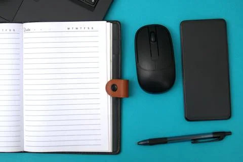 The notebook is open on the laptop next to the smartphone Stock Photos