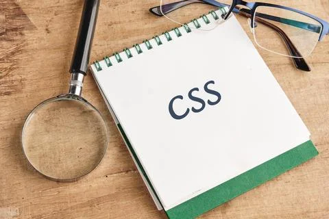 A notebook open to the page labeled with CSS sits on a wooden desk alongside  스톡 사진