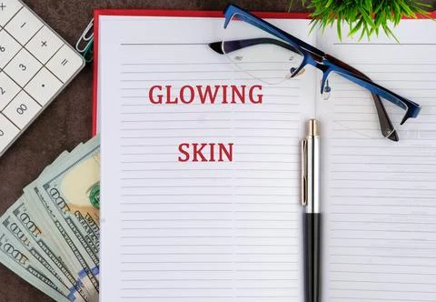 A notebook open to a page titled glowing skin, accompanied by glasses, a pen, Stock Photos