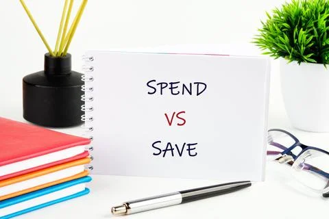 A notebook is open on a table showing spend versus save. There are colored no 스톡 사진