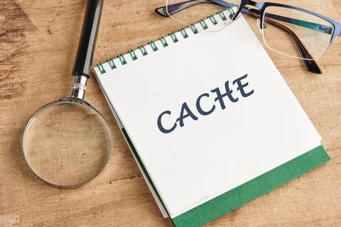 A notebook opened to a page labeled CACHE sits on a wooden table accompanied  Stock Photos