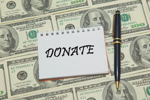 Notebook page with text DONATE on dollar background Stock Photos