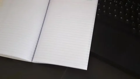 Notebook Pages Turning by Wind Near Laptop Workspace Video stock 335576490