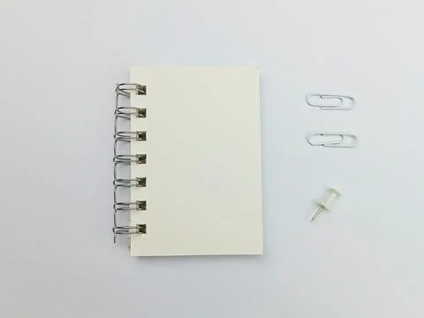 Notebook with paper clips and push pin on white background Stock Photos