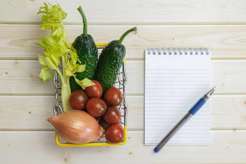 Notebook, pen and different vegetables from the regular diet on the backgroun Foto stock