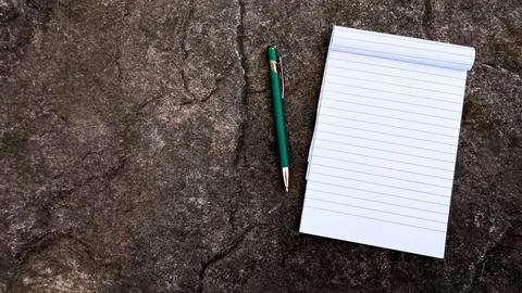 Notebook with pen on a stone surface with copy space Stock Photos