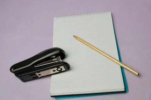 Notebook with pencil and stapler on the table Stock Photos
