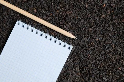 Notebook with pencil on the background of black tea. Stock Photos