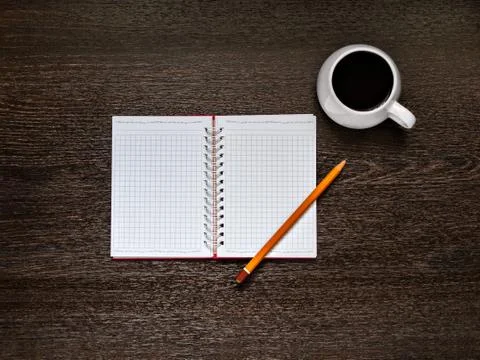 Notebook, pencil, cup of coffee are on the wooden background Stock Photos