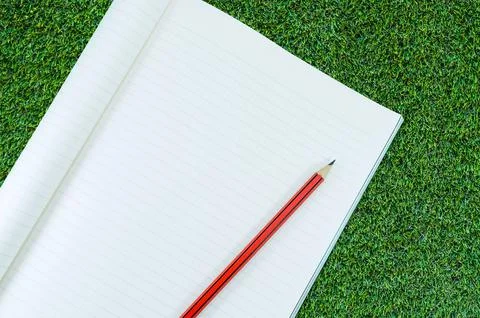 Notebook with pencil isolate on green grass background,for art education back Stock Photos