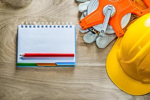 Notebook Pencil Protective gloves Measuring tape Hard hat on wooden board Stock Photos