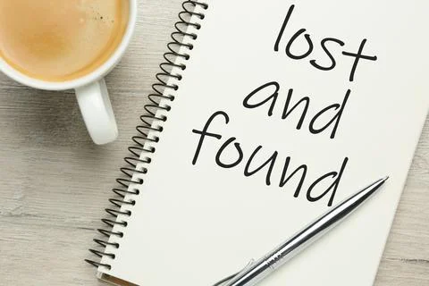 Notebook with phrase Lost and Found, cup of coffee and pen on white wooden ta Stock Photos