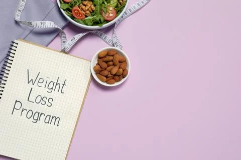 Notebook with phrase Weight Loss Program, bowl of salad and almonds on pink.. 스톡 사진