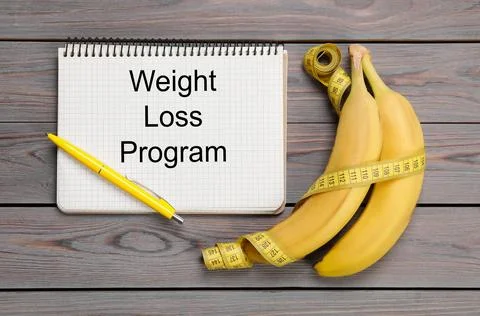 Notebook with phrase Weight Loss Program, measuring tape and bananas on gre.. Stock Photos