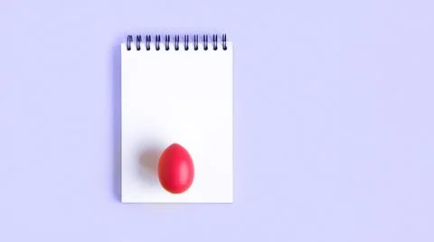 Notebook with red Easter Egg. Spiral notepad on spring violet background. Top Stock Photos