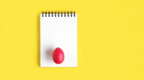 Notebook with red Easter Egg. Spiral notepad on spring yellow background. Top Stock Photos