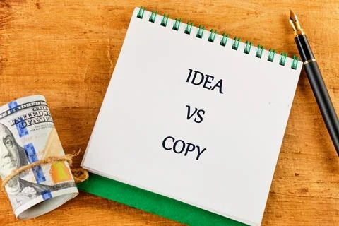A notebook shows the words idea and copy on opposite pages. A roll of money a Stock Photos