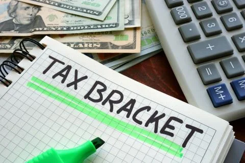 Notebook with sign tax bracket on a table. Stock Photos