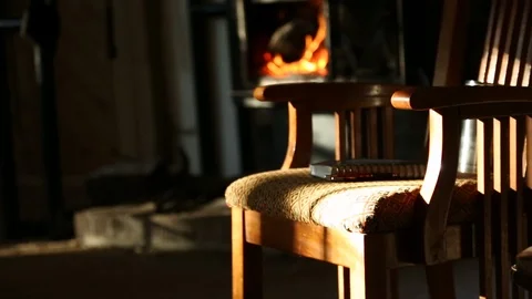 Notebook Sits On Chair In Warm Sunlight As Fire Crackles In Background 스톡 동영상 125540063