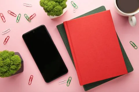 Notebook with smartphone and cup of coffee on pink background. Stock Photos
