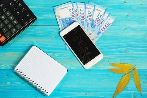 A notebook, a smartphone with a broken screen and new Russian banknotes lie o Stock Photos