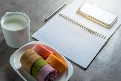 Notebook, smartphone, jam roll, cup of milk, pen on wooden, Business, educati Stock Photos