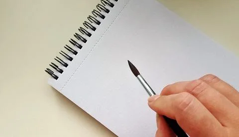Notebook with spiral Notebook template mock up for artwork with hand with brush Stock Photos