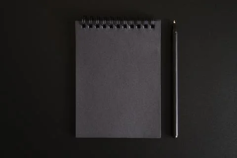 Notebook on a spring with black sheets and a pen on a black background. space Stock Photos