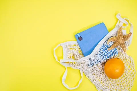 Notebook with starfish and orange with string bag on yellow background Stock Photos
