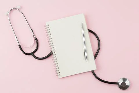 Notebook with stethoscope on a pink table. Stock Photos