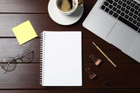 Notebook, sticky note, pen, binder clips, coffee, glasses and laptop on woo.. Stock Photos
