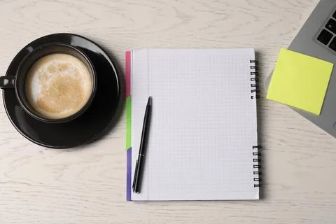 Notebook, sticky note, pen, coffee and laptop on white wooden table, flat lay Stock Photos
