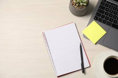 Notebook, sticky note, pen, coffee, floral decor and laptop on wooden table.. Stock Photos