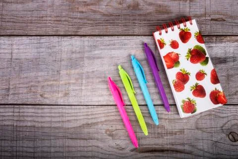 Notebook with strawberries and set of colored pens on wooden background Stock Photos