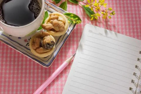 Notebook on table with cup of coffee and dessert. Stock Photos
