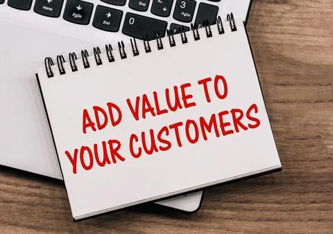 A notebook with the text ADD VALUE TO YOUR CUSTOMERS lies on a laptop stand.. 스톡 일러스트